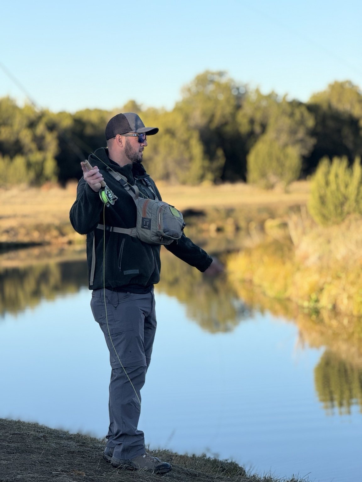 Fly angler casting beside calm western water at golden hour