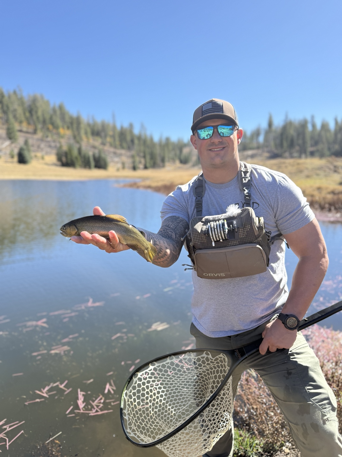 Angler holding a trout near a mountain lake