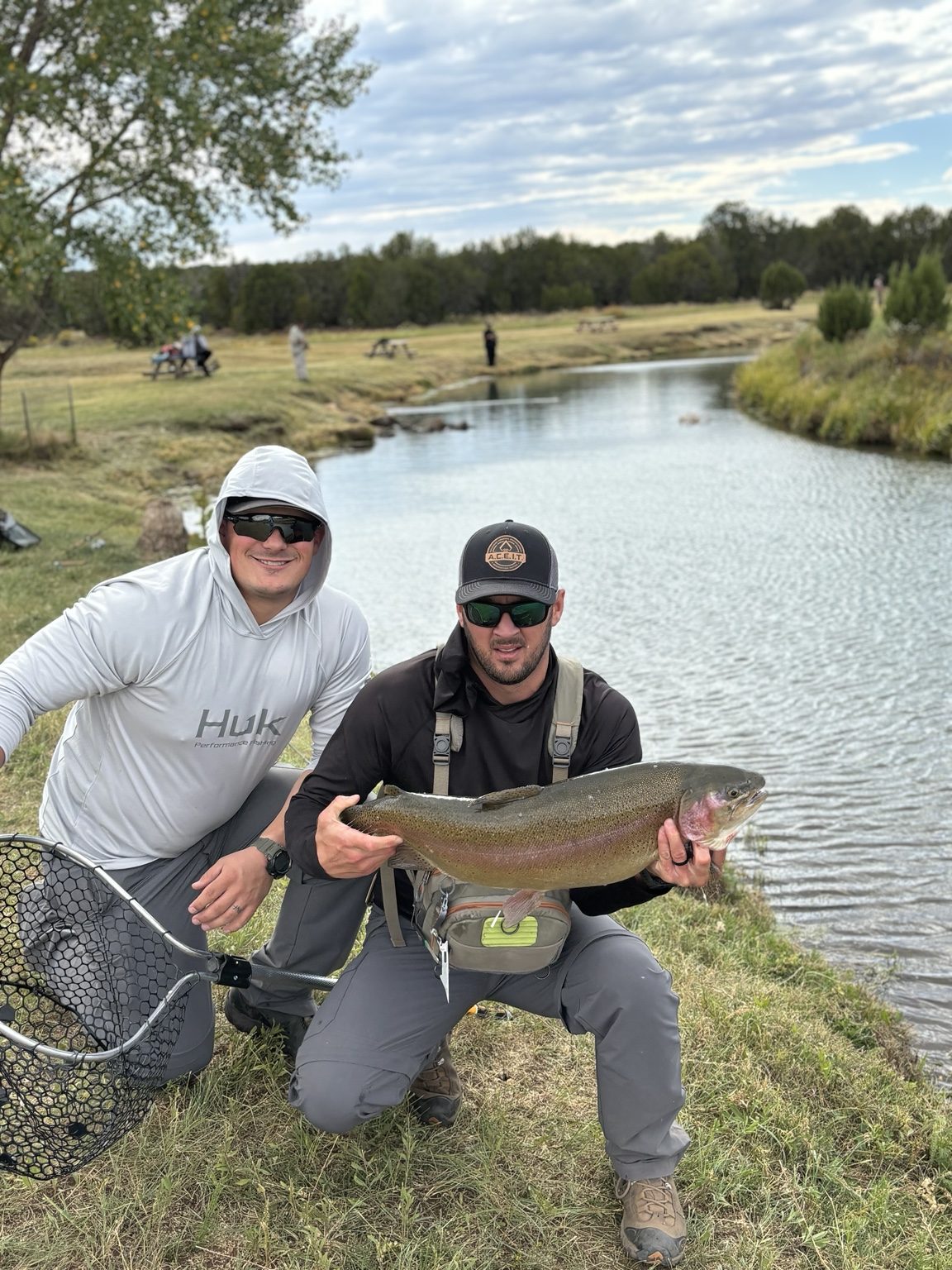 Two anglers posing with a large rainbow trout